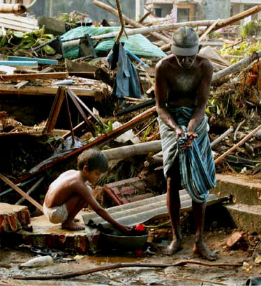 A man and young boy wash their hands in the middle of a destroyed area in Sri Lanka