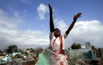 A woman extends her arms to the sky as she grieves the loss of her child